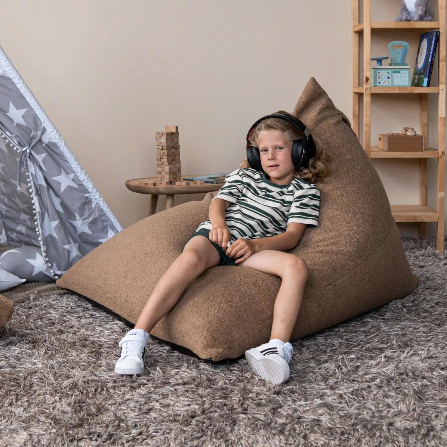 Ett barn som sitter på en mysig barnfåtölj till barnrum och lyssnar på musik.