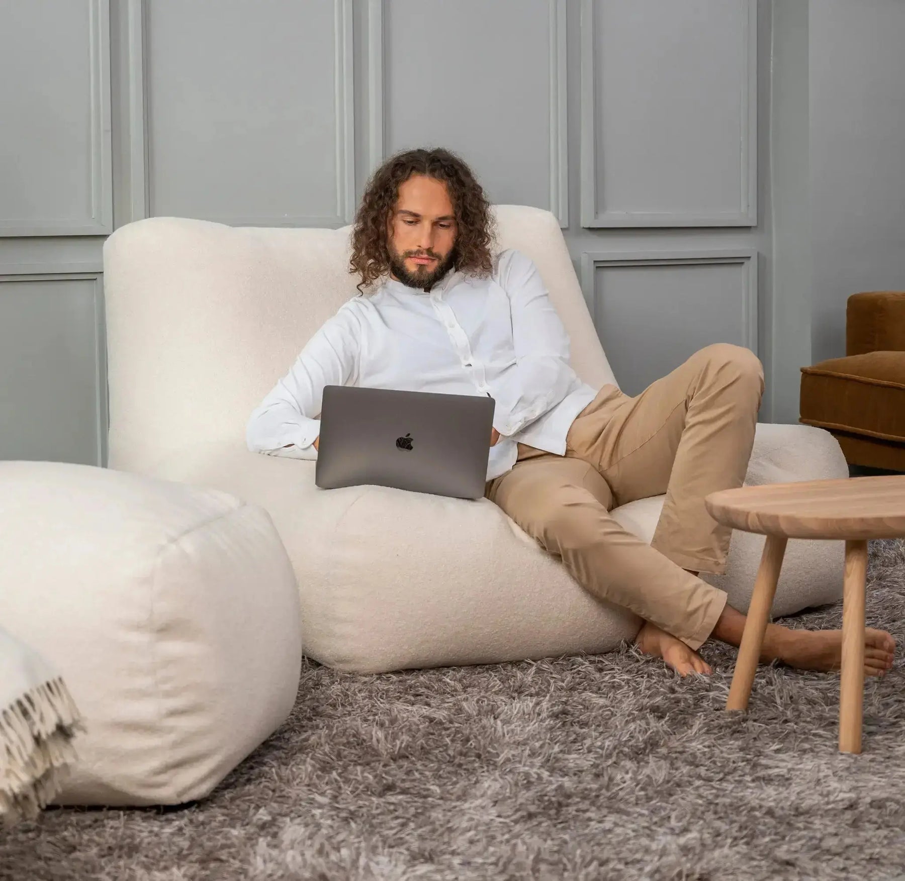 Man som sitter bekvämt i handgjorda saccosoffor och arbetar på sin laptop.