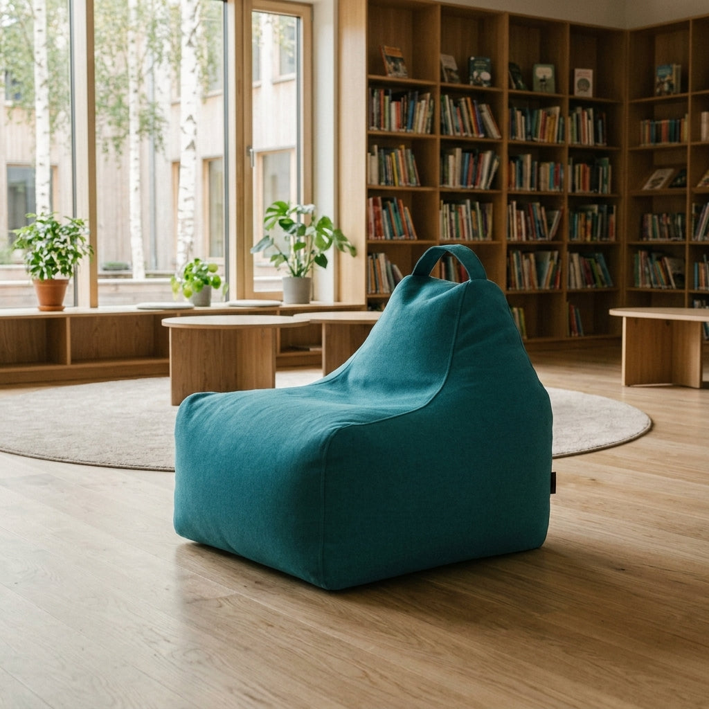 Modern library reading nook featuring a teal beanbag chair, wooden bookshelves, and indoor plants in a bright, airy space.