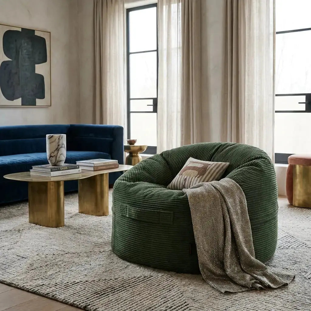 Modern living room featuring a green corduroy beanbag chair, blue sofa, brass coffee table, and abstract wall art.