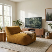 Modern living room with a mustard corduroy lounge chair, wooden media console, and cozy neutral rug in a minimalist home.