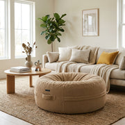 Saccosäck Roll 135 Teddy Camel bean bag in a cozy, modern living room with a neutral sofa and round wooden coffee table.