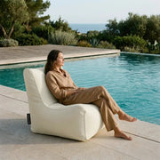 Sittsäck Fåtölj Seat 100 Colorin Ivory displayed as a comfortable outdoor lounge chair by a serene swimming pool.
