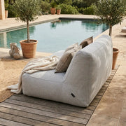 Sittsäck Soffa Tube Dunẽs Fluffy White styled on a wooden deck by a pool with a cozy throw and decorative pillows.