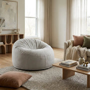 Modern living room featuring a cozy white boucle beanbag chair, wooden coffee table, and soft neutral decor.
