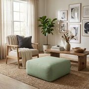 Sittsäck Tube Sittpuff 80 Dunẽs Sedge styled as a sage green ottoman in a bright, modern living room with a cozy armchair.