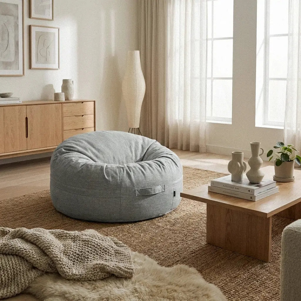 Modern minimalist living room featuring a grey bean bag chair, wooden coffee table, and neutral decor in a cozy, airy space.
