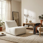Modern minimalist living room featuring a cozy white boucle lounge chair, textured area rug, and warm neutral decor.