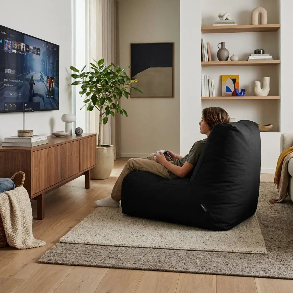 A person gaming in a Sittsäck Tube OX Black bean bag chair, showcased in a modern, minimalist living room setting.